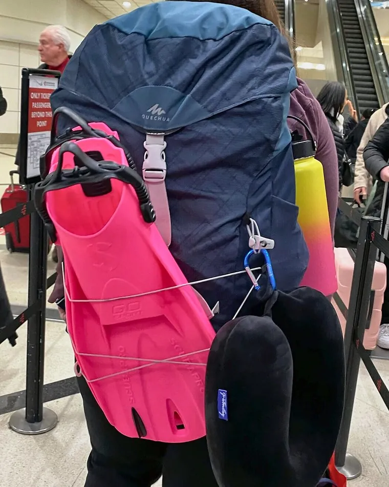 Pink fins strapped to a backpack in an airport queue