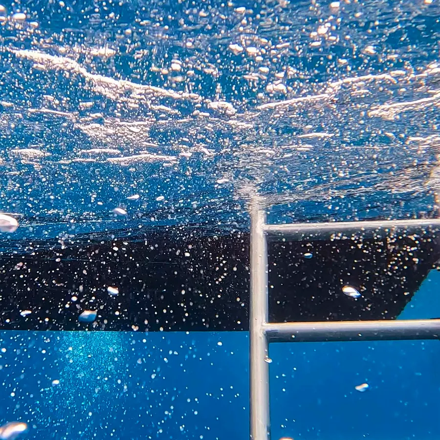 Bubbles rising to the surface beside a dive boat ladder