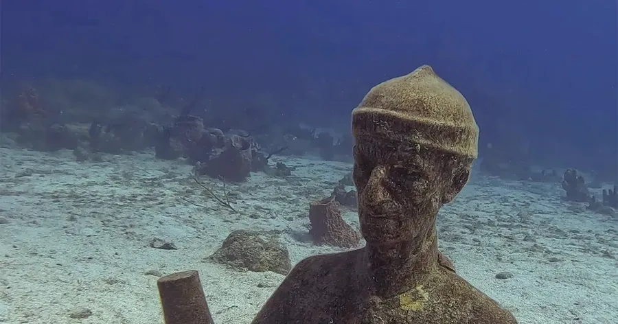A sunken statue on the sandy seabed