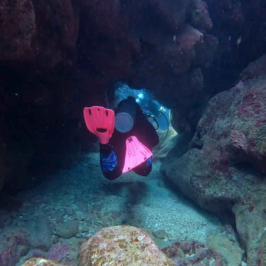 Pink fins at the entrance of an underwater cave