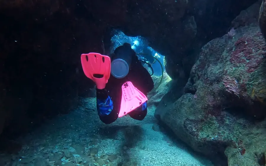 Mariya in pink fins at the mouth of an underwater tunnel