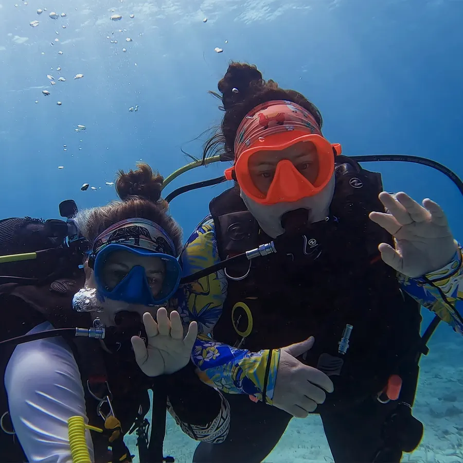 Mariya and Sam waving at the camera underwater