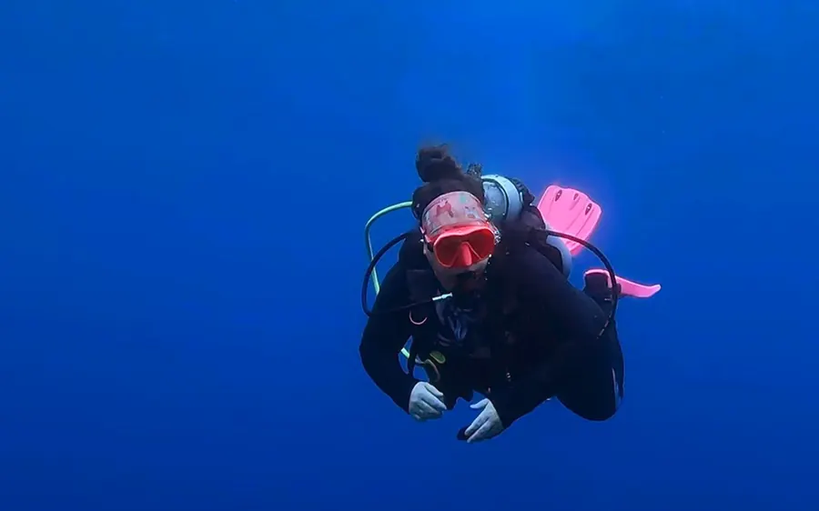 Mariya diving in open blue water in pink fins