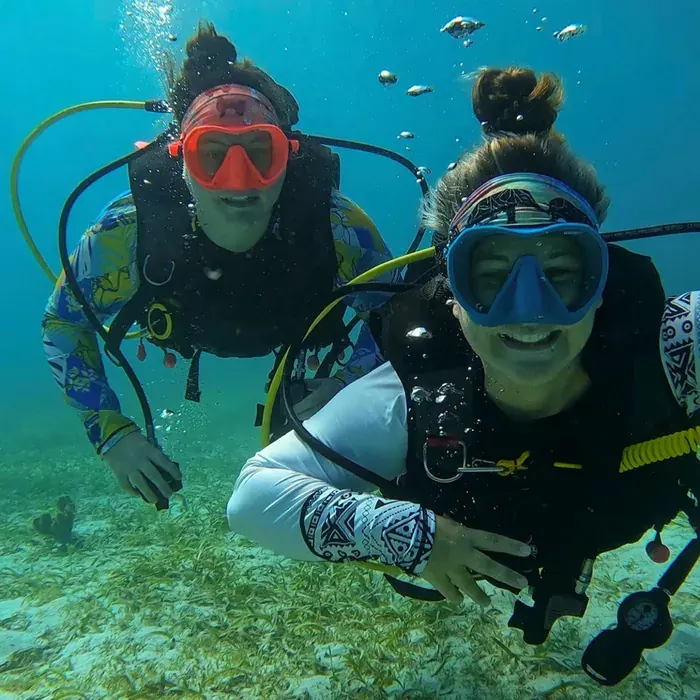 Mariya and Sam scuba diving together over the sand